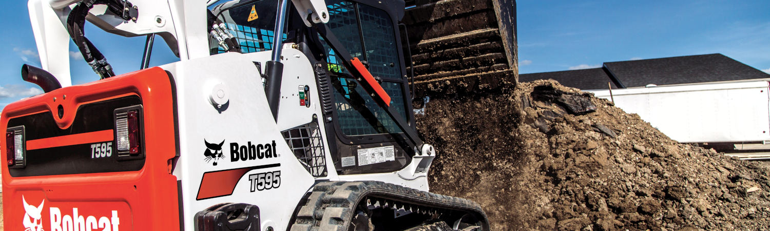 An orange, white, and black Bobcat® T595 skid steer digging up dirt.